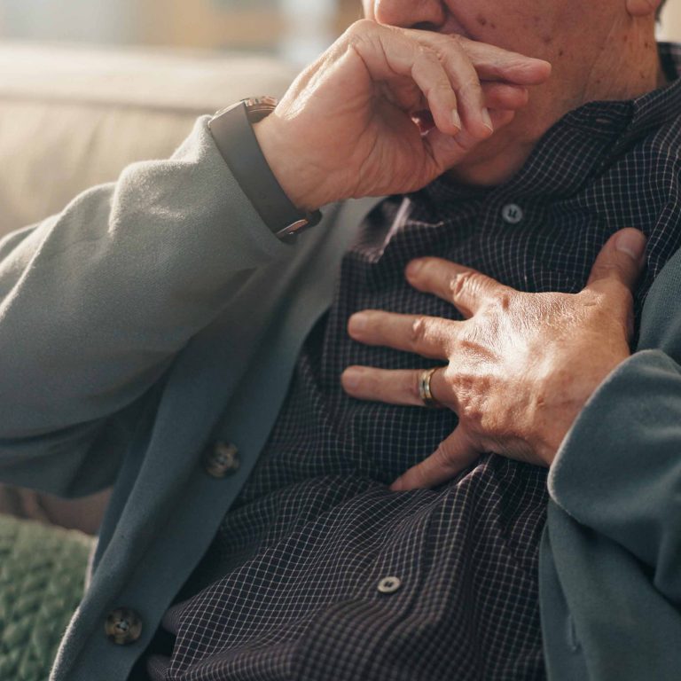 Homem idoso com a mão no peito sentindo dor torácica.
